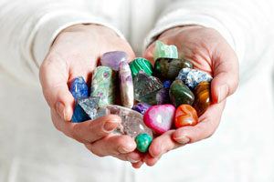 Two hands forming a heart shape holding spiritual gemstones